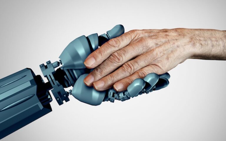 Primo piano di mano di robot umanoide che stringe la mano di un anziano su sfondo bianco, a esprimere il concetto di intelligenza artificiale per assistenza anziani.